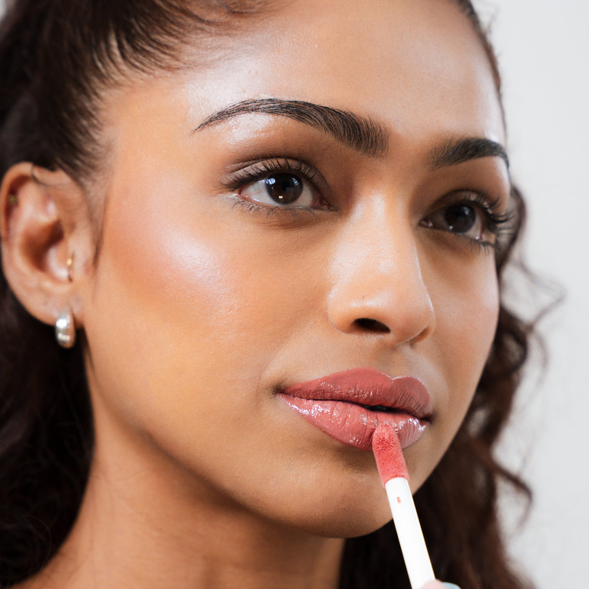 Peptide Glo Lip Glaze in Flirt on tan skin