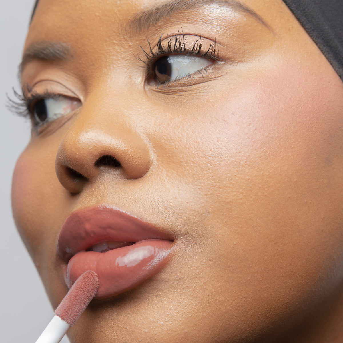 Peptide Glo Lip Glaze in Veil on tan skin